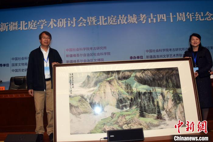 开幕式上，陈星灿(左)代表中国社会科学院考古研究所接受新疆昌吉州赠送的绘画作品。　孙自法 摄